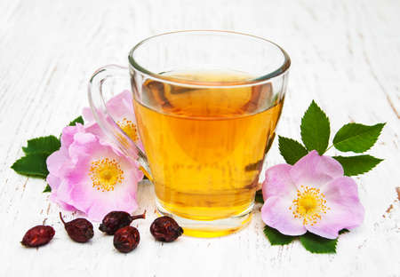 Cup of tea and dogrose on a old wooden backgroundの写真素材
