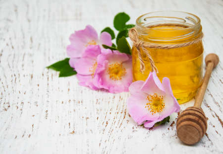 Honey and dog rose flowers on a old wooden backgroundの写真素材