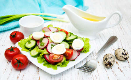Spring salad with tomato, cucumbers and radish on a wooden backgroundの写真素材