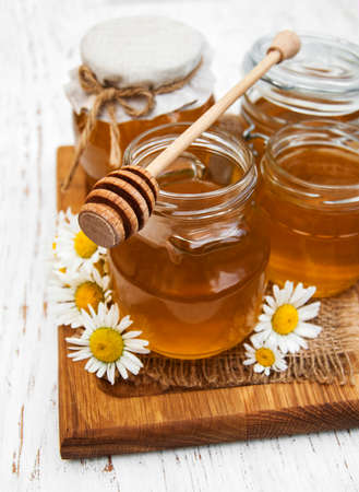 Jars of honey with camomile on a old wooden backgroundの写真素材