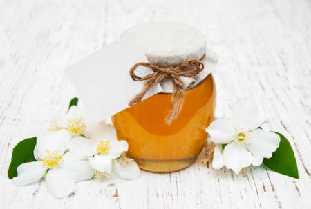 Honey with jasmine flowers on a wooden backgroundの写真素材