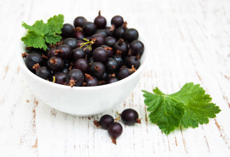 Bowl with black currant on a wooden backgroundの写真素材