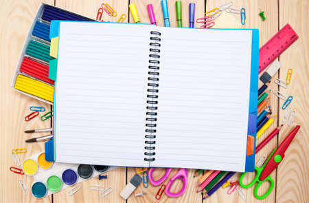 Notebook with school supplies on a wooden background