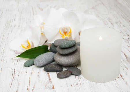 Spa stones, orchids and candle on a wooden backgroundの写真素材