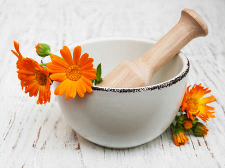 flower of calendula officinalis in mortar on a wooden backgroundの写真素材