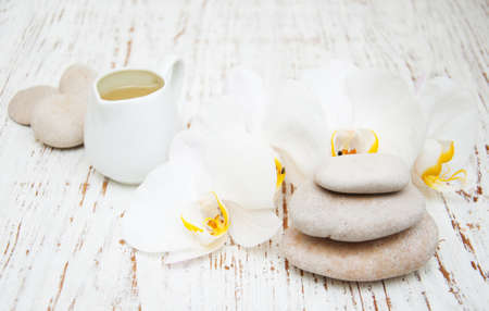 White orchids, oils and massage stones on a wooden backgroundの写真素材