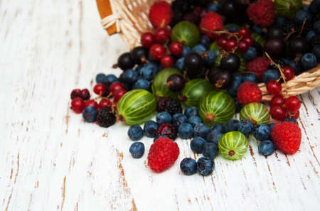 Fresh berries with basket  on a wooden background