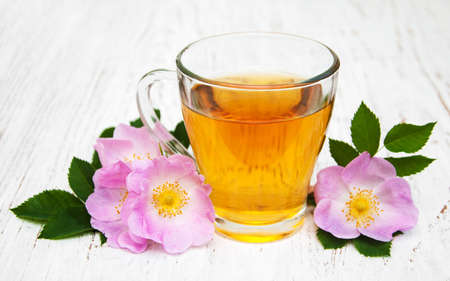 Cup of tea and dogrose on a old wooden backgroundの写真素材