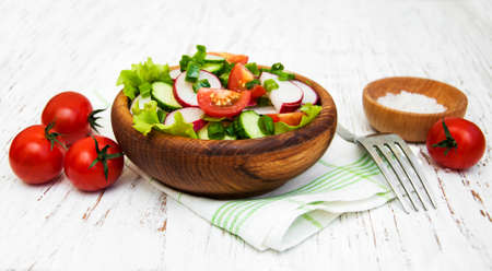 Spring salad with tomato, cucumbers and radish on a wooden backgroundの写真素材