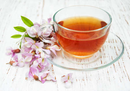 Cup of tea and acacia flowers on a wooden backgroundの写真素材