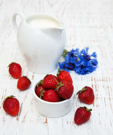 Jug of milk, strawberries and wildflowers on a old wooden backgroundの写真素材