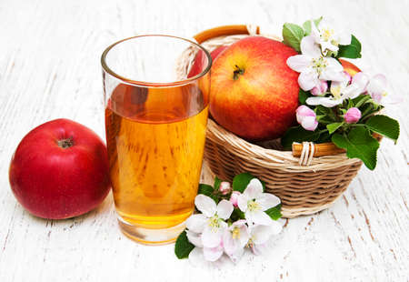 glass of apple juice with apples and flowers on a wooden backgroundの写真素材