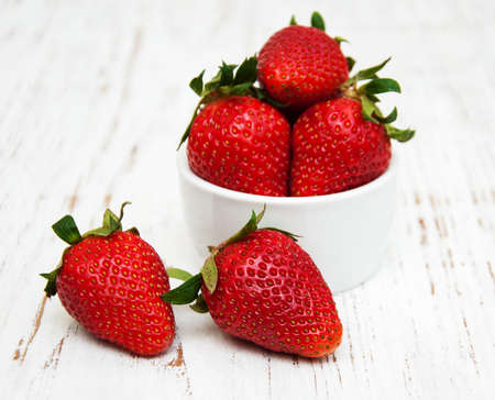 Bowl with strawberries on a old wooden backgroundの写真素材