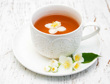 Cup of tea with jasmine flowers on a wooden backgroundの写真素材