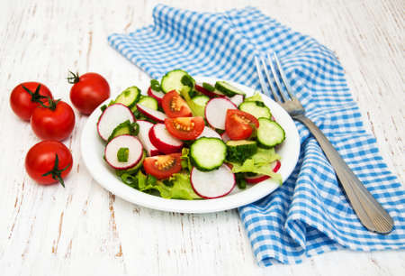 Spring salad with tomato, cucumbers and radish on a wooden backgroundの写真素材