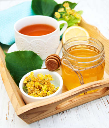 cup of herbal tea with honey and  linden flowers on a old wooden backgroundの写真素材