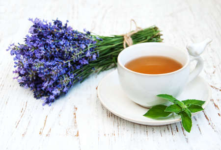 Cup of tea and lavender flowers on a old wooden backgroundの写真素材