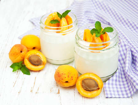 sweet yogurt with fresh apricots on a wooden backgroundの写真素材
