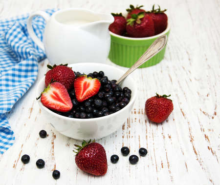 Bowl with blueberries and strawberries on a old wooden backgroundの写真素材