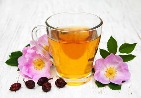 Cup of tea and dogrose on a old wooden backgroundの写真素材