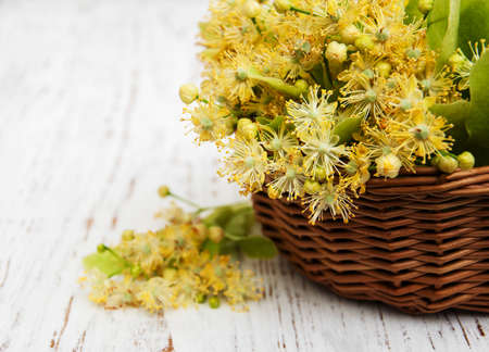 wicker basket with lime flowers on a old wooden backgroundの写真素材