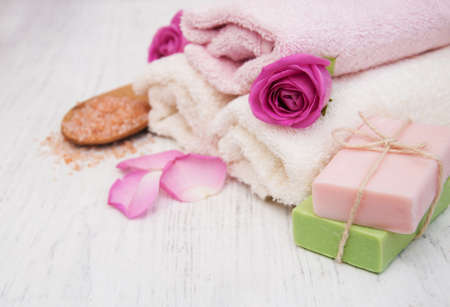 Bath towels, salt and soap with pink roses on a old wooden backgroundの写真素材