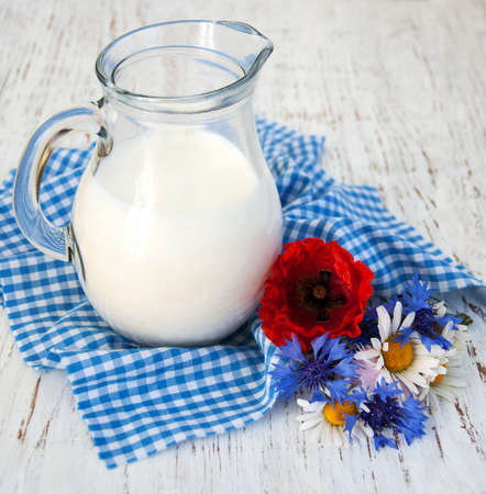 Jug of milk and wildflowers on a old wooden backgroundの写真素材