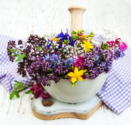 wild flower and herb leaf in mortar on a wooden backgroundの写真素材
