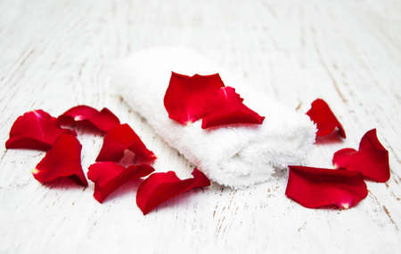 Massage towels and red roses petals on a wooden backgroundの写真素材