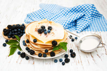 Pancakes with fresh berries on a wooden tableの写真素材