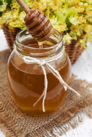 Jar with honey and linden flowers on a wooden backgroundの写真素材