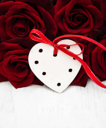 Fresh Red roses and wooden heart on a wooden backgroundの写真素材