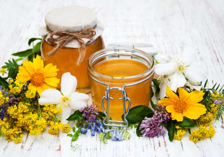 Honey and wild flowers on a wooden backgroundの写真素材