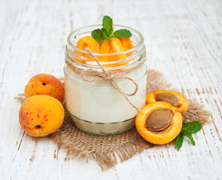 sweet yogurt with fresh apricots on a wooden backgroundの写真素材