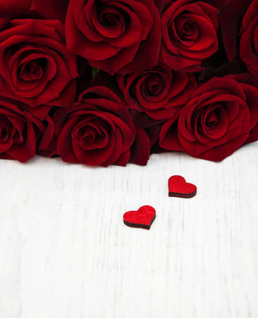 Fresh Red roses and wooden heart on a wooden backgroundの写真素材