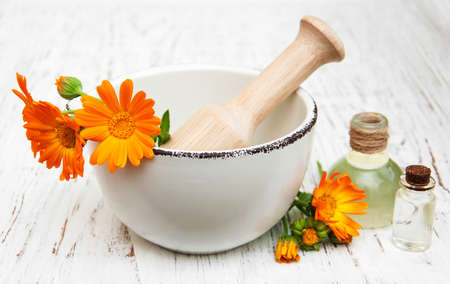 calendula flowers in mortar and massage oil on a wooden backgroundの写真素材