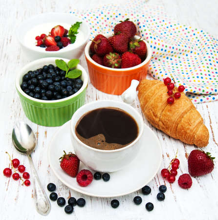 Fresh berries, coffee and croissant on a wooden backgroundの写真素材