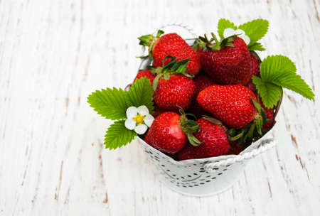 Metal pot with strawberries on a wooden backgroundの写真素材