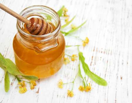 Jar with honey and linden flowers on a wooden backgroundの写真素材