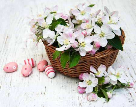 Basket with apple blossom and easter eggs on a wooden backgroundの写真素材
