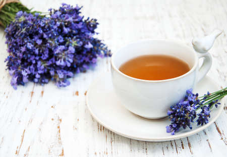 Cup of tea and lavender flowers on a old wooden backgroundの写真素材