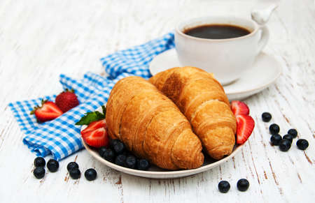 Fresh berries, coffee and croissant on a wooden backgroundの写真素材