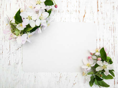 Apple blossoms with card on a old white wooden background
