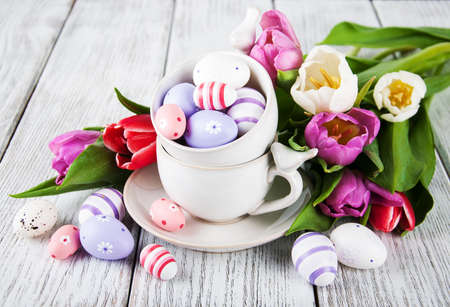 Easter eggs and tulips on a wooden tableの写真素材