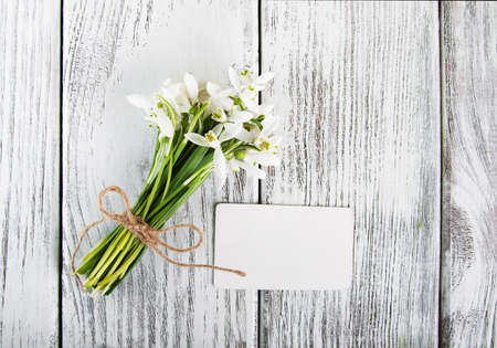 snowdrops flowers with card on a wooden tableの写真素材
