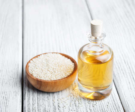 Sesame seeds and bottle with oil on a old wooden tableの写真素材