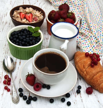 Fresh berries, coffee and croissant on a wooden backgroundon a wooden backgroundの写真素材