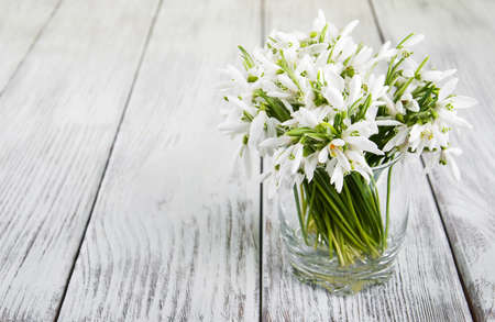 bouquet of snowdrops in a glass on a old wooden tableの写真素材