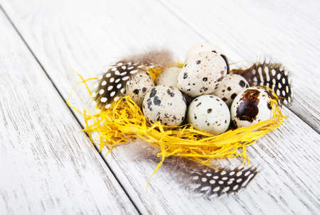 quail eggs in nest on a old wooden tableの写真素材
