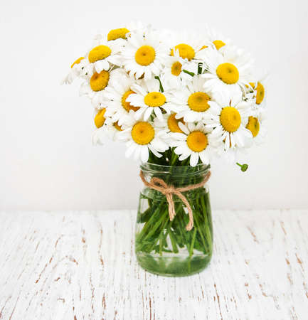 bouquet of daisies in a vase on a old wooden backgroundの写真素材